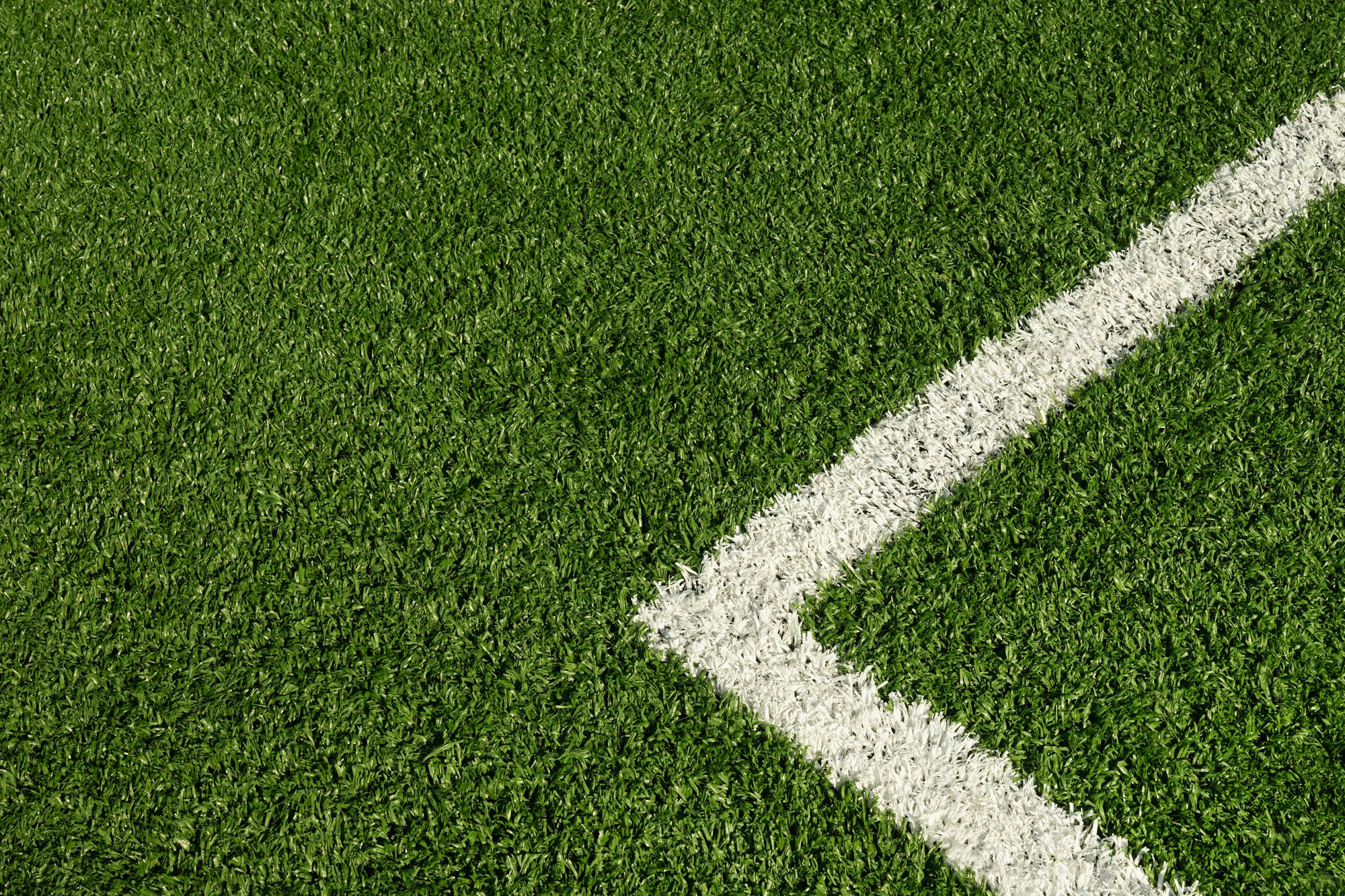 Artificial green grass with white stripe of soccer field.